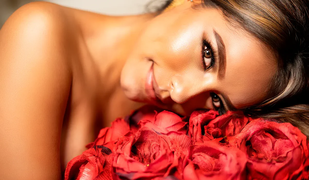 Lächelnde Frau mit strahlender Haut, ruhend auf roten Rosen