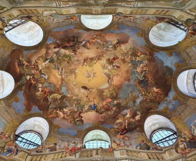 Ornate ceiling fresco with clouds and figures, Viennese architecture.