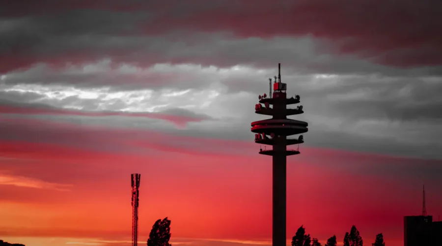 Silhouette of telecommunications towers against a fiery red sunset sky.