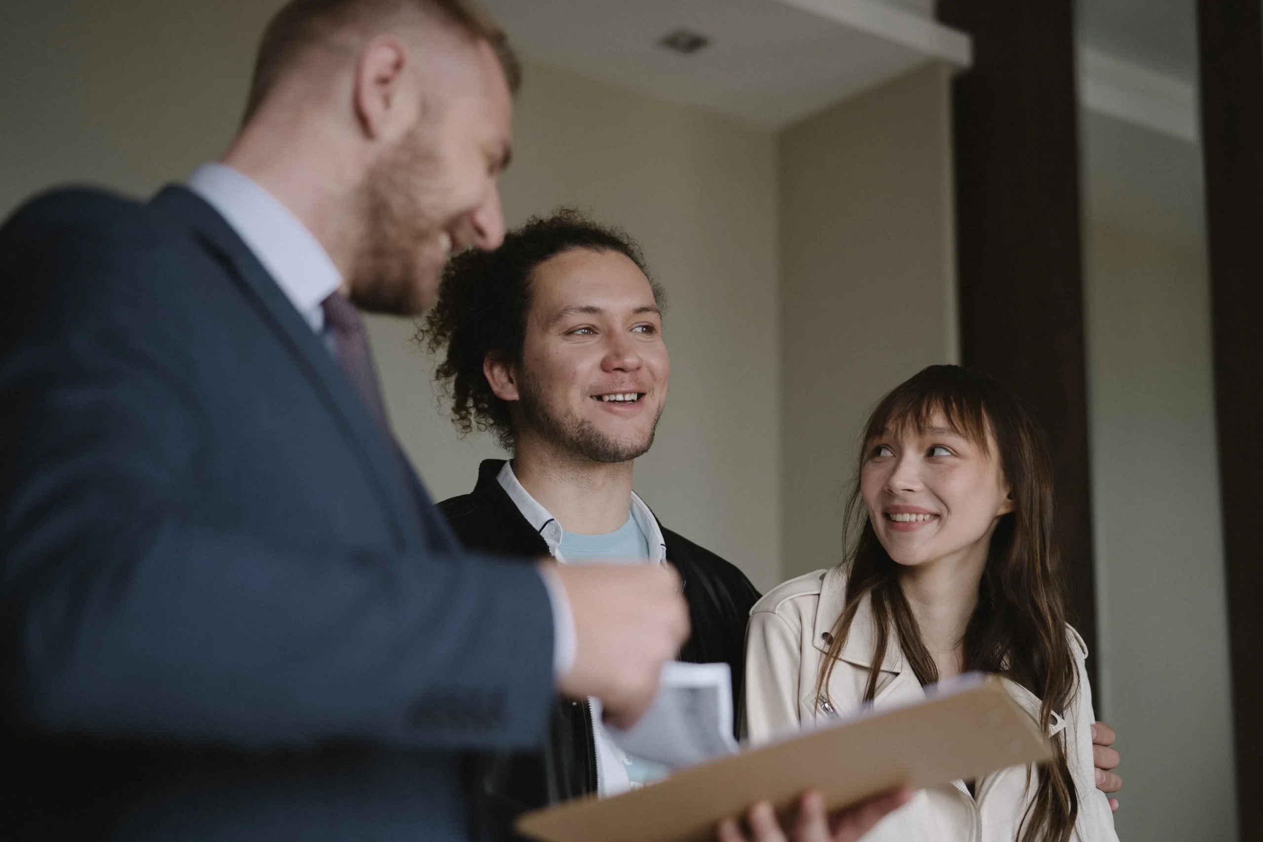 Real estate agent with happy couple holding documents and smiling.