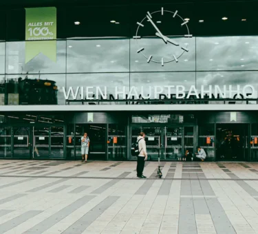 Wien Hauptbahnhof entrance with clock and people passing by.