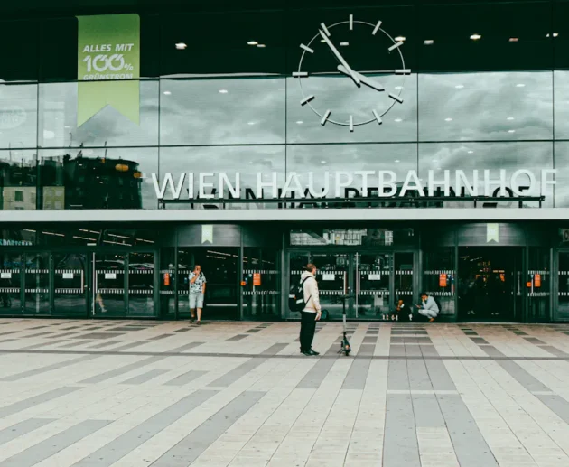 Wien Hauptbahnhof entrance with clock and people passing by.