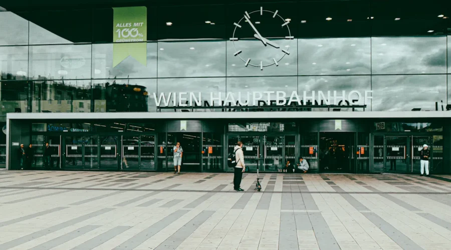 Wien Hauptbahnhof entrance with clock and people passing by.