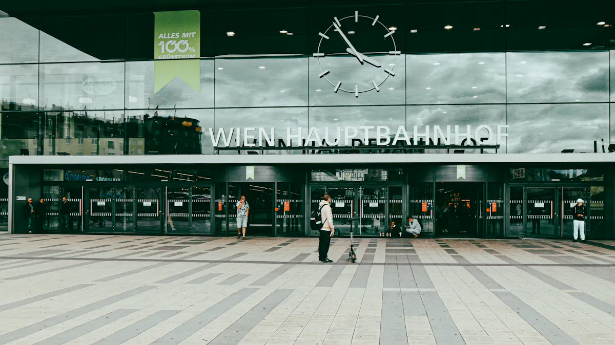 Wien Hauptbahnhof entrance with clock and people passing by.